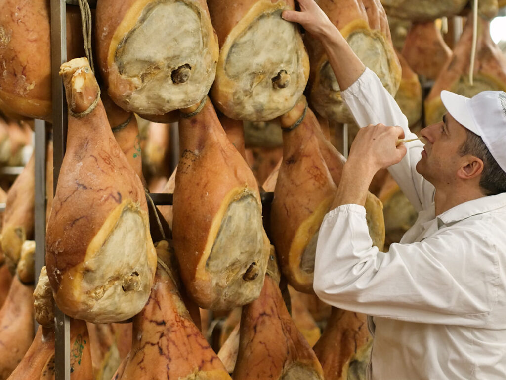 ITS__0005_Parma, a man in charge of quality control walks between the hams and controls, the perfume and the certified I